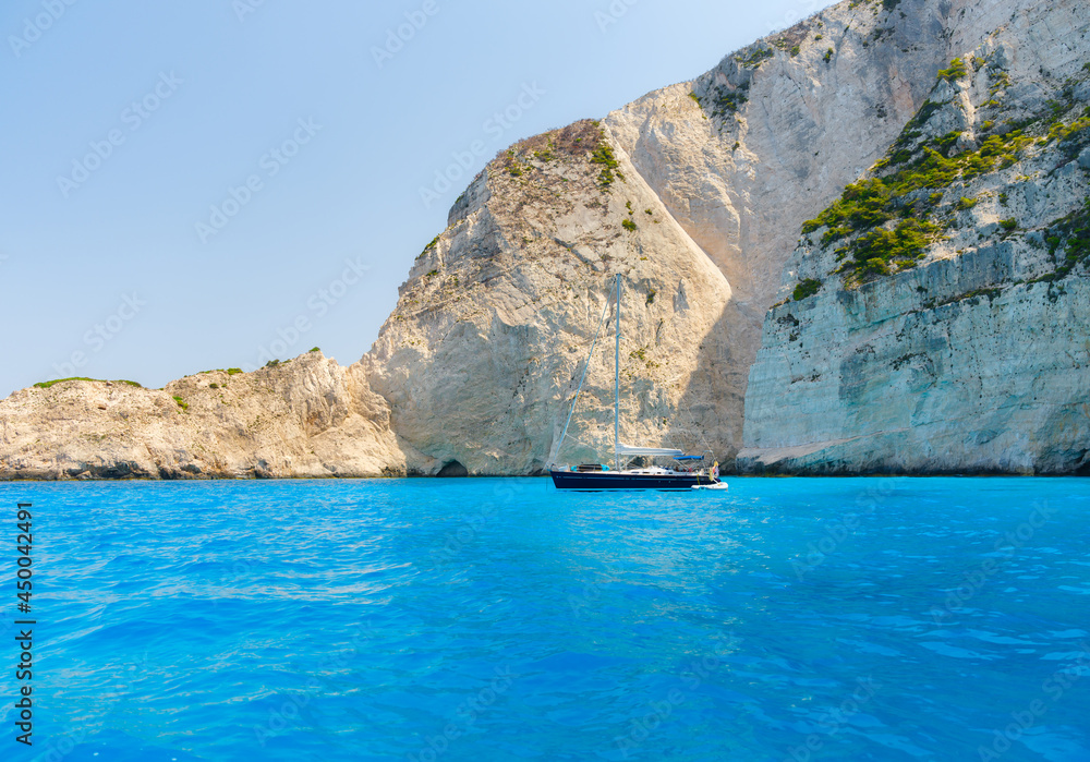 Sailing yacht in the bay. Rocks and bright turquoise sea water. Azure water in the Mediterranean Sea. Summer vacations and travels on a big boat.