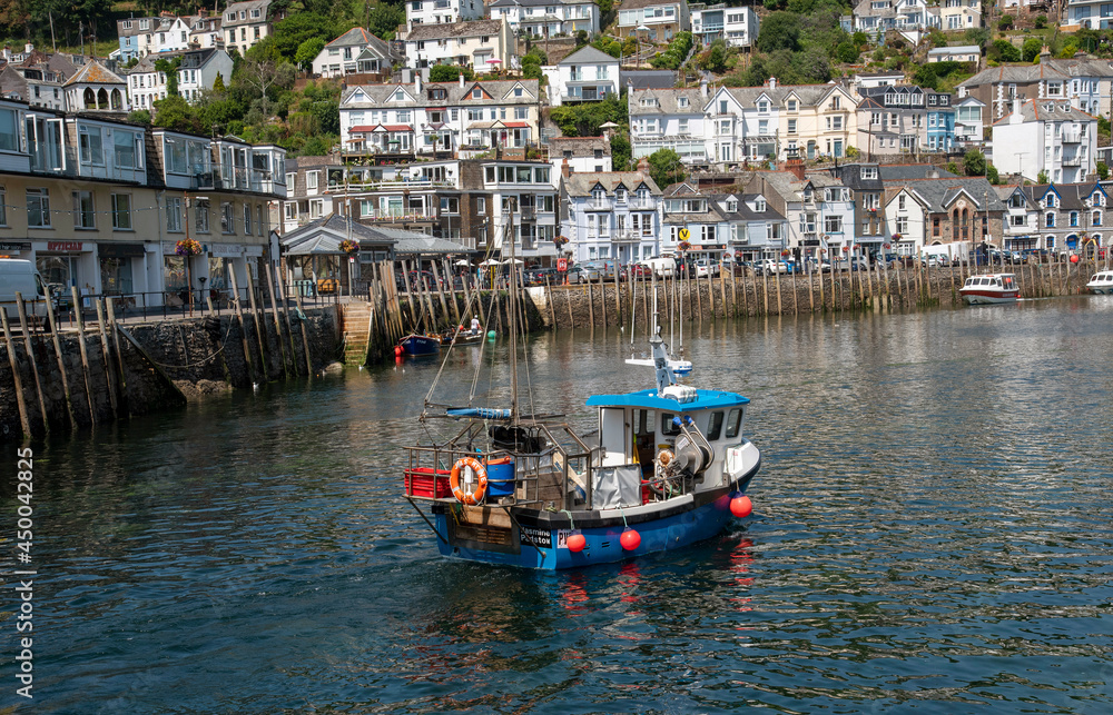 Looe, Cornwall, England, UK. 2021. Fishing boat on an incoming tide with a background of the scenic West Looe a resort in Cornwall, UK.