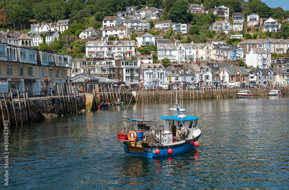 Looe, Cornwall, England, UK. 2021. Fishing boat on an incoming tide with a background of the scenic West Looe a resort in Cornwall, UK.