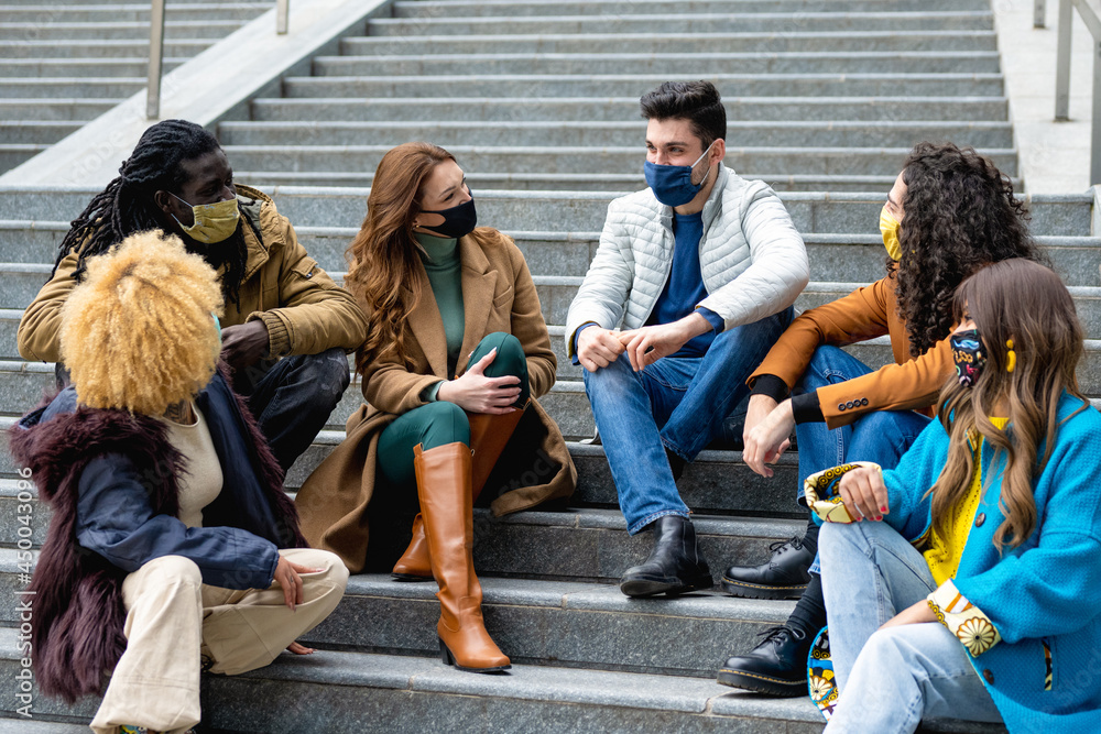 Fototapeta premium group of millennial friends chatting together and having fun, universitary students from different ethnicity smiling and wearing facemask for preventin infection