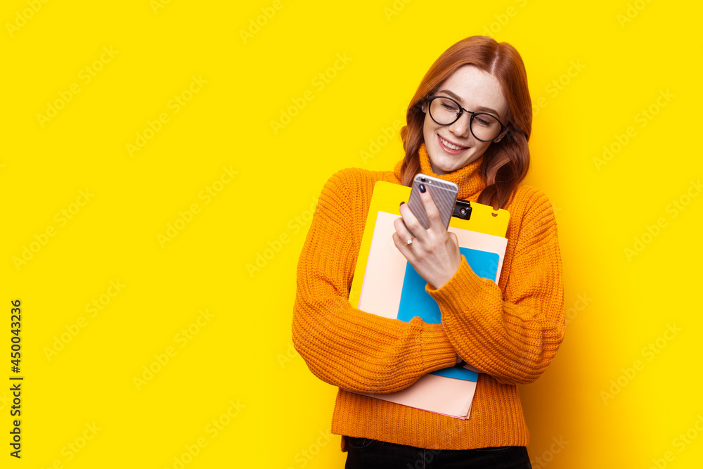 Freckled ginger student using phone on yellow background. Sms chat. Educational concept Freckled ginger student using phone on yellow background. Sms chat. Educational concept