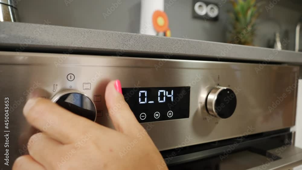 Adult Caucasian woman's hand operating oven buttons Adult Caucasian woman's hand operating oven buttons