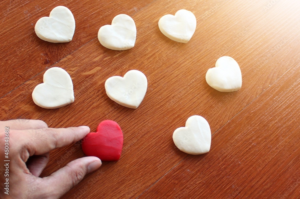 Obraz premium Hand pick up red heart over white heart. Searching for love, looking for real love, valentine's day concept