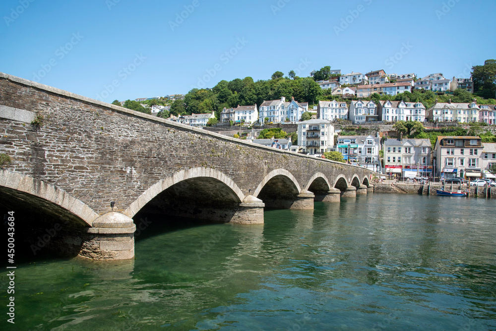 Looe, Cornwall, England, UK. 2021.  Stone road bridge crossing the tidal River Looe which devides East and West Looe