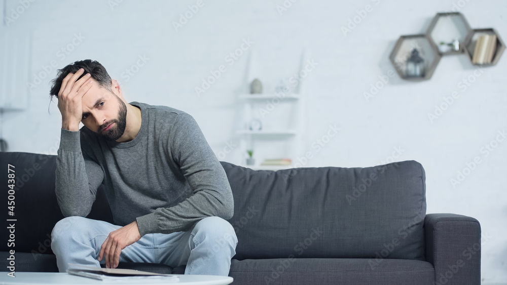 stressed man looking away while sitting near folder on coffee table stressed man looking away while sitting near folder on coffee table