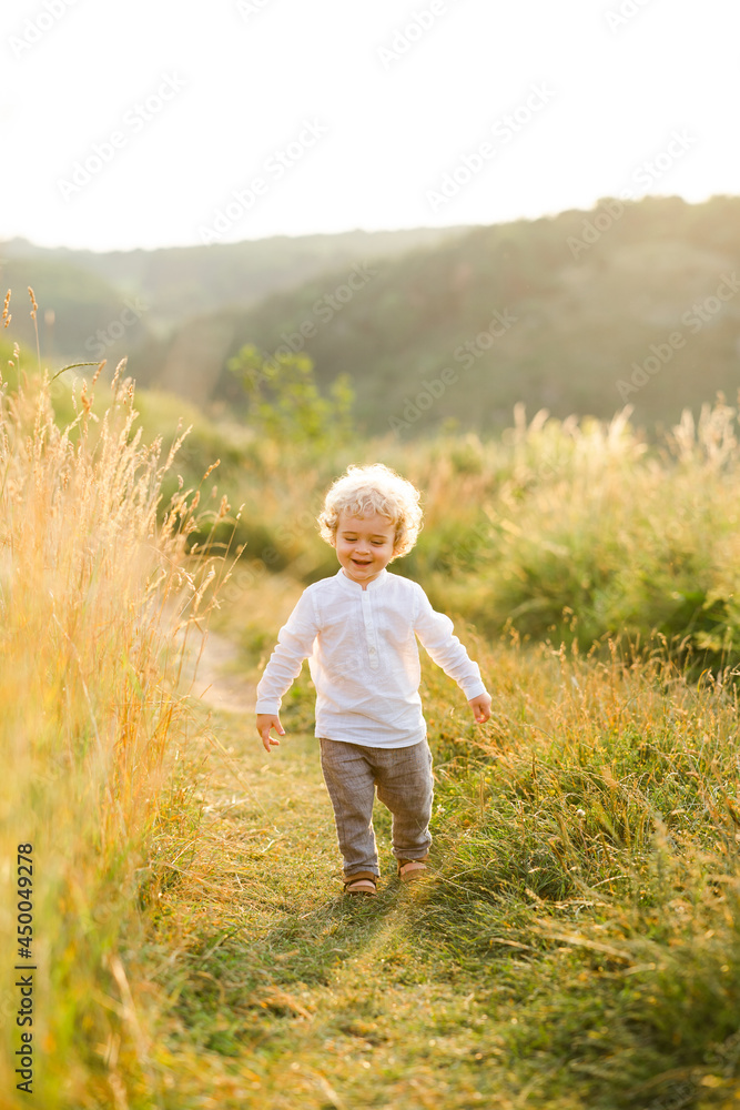 Happy boy with curly blond hair walks in nature Happy boy with curly blond hair walks in nature