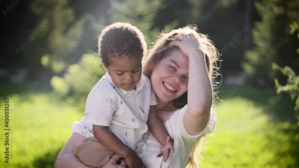Happy light-skinned European woman holds African baby girl in her arms. Happy light-skinned European woman holds African baby girl in her arms.