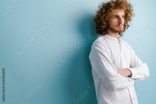 Young man with ginger curly hair posing and looking aside