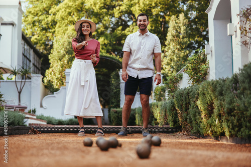 Happy tourist couple playing petanque together photo