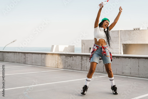 Black young woman laughing and dancing on parking outdoors