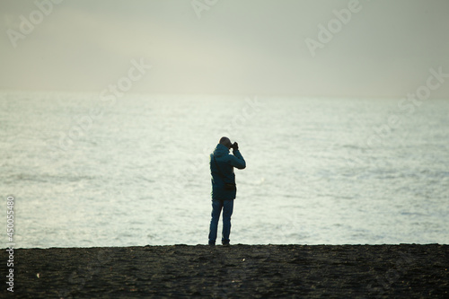 Sole tourist taking picture on the seashore in Iceland