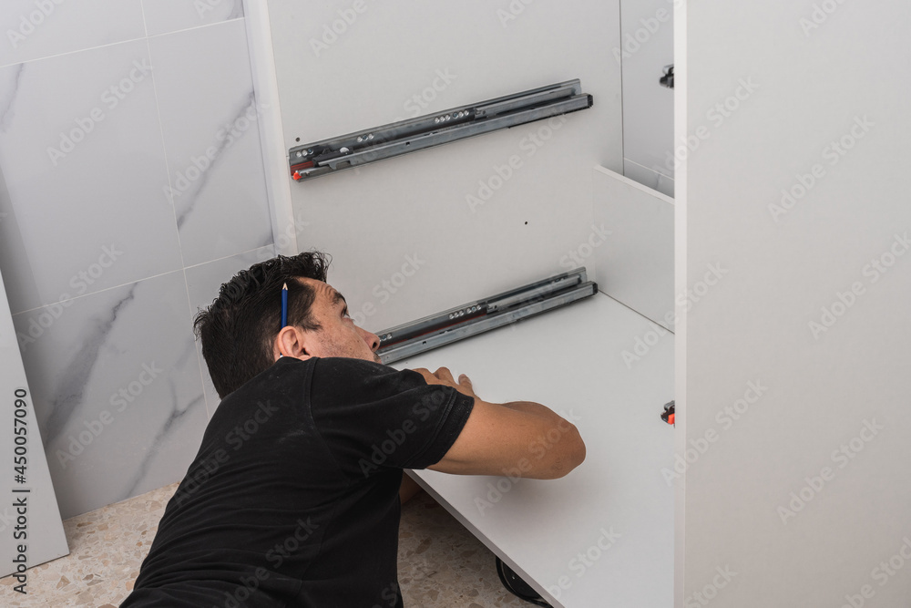 Man lying on the floor while installing furniture Man lying on the floor while installing furniture