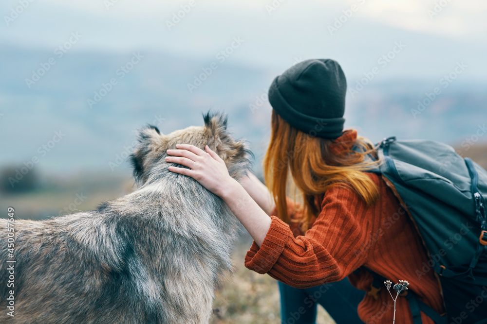 woman tourist with backpack playing with dog on nature travel