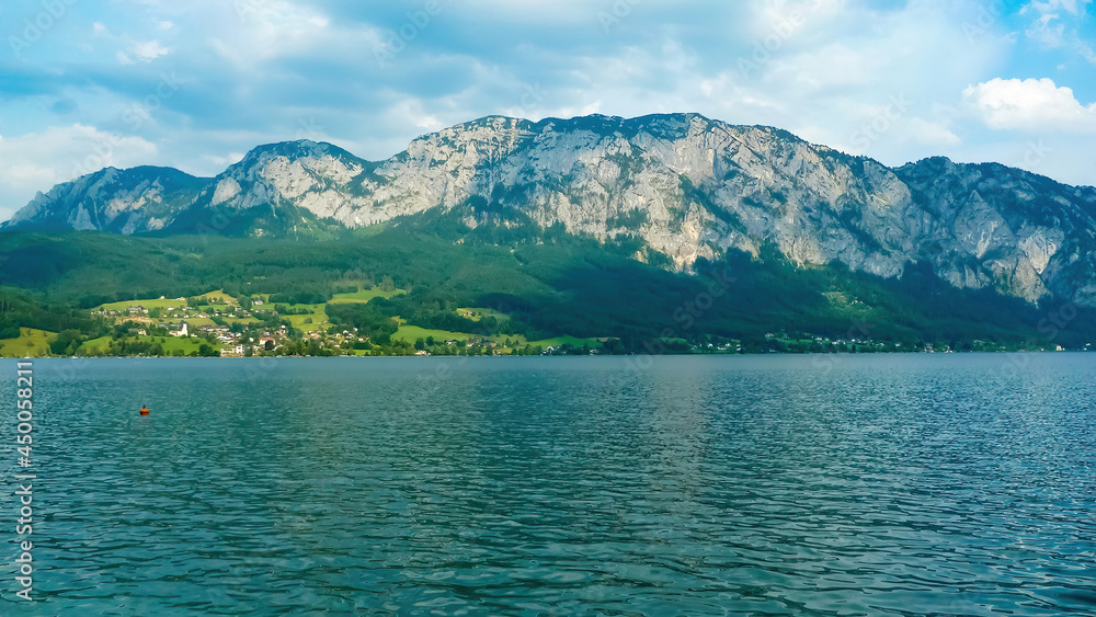 View over lake on mountain scenery with blue sky and clouds in summer - Attersee, Austria