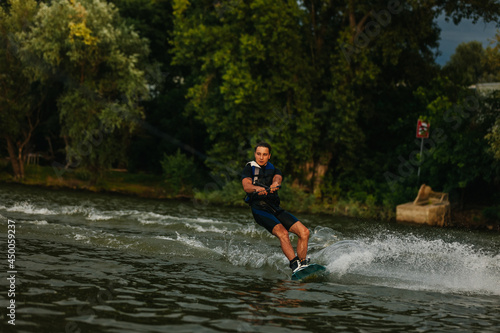 Young man riding wake-board on lake