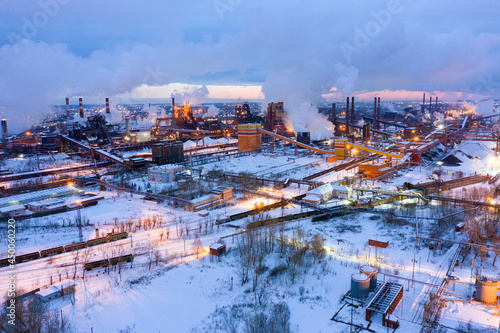 Aerial view of metallurgical plant blast furnace at night with smokestacks and fire blazing out of the pipe. Industrial panoramic landmark with blast furnance of metallurgical production