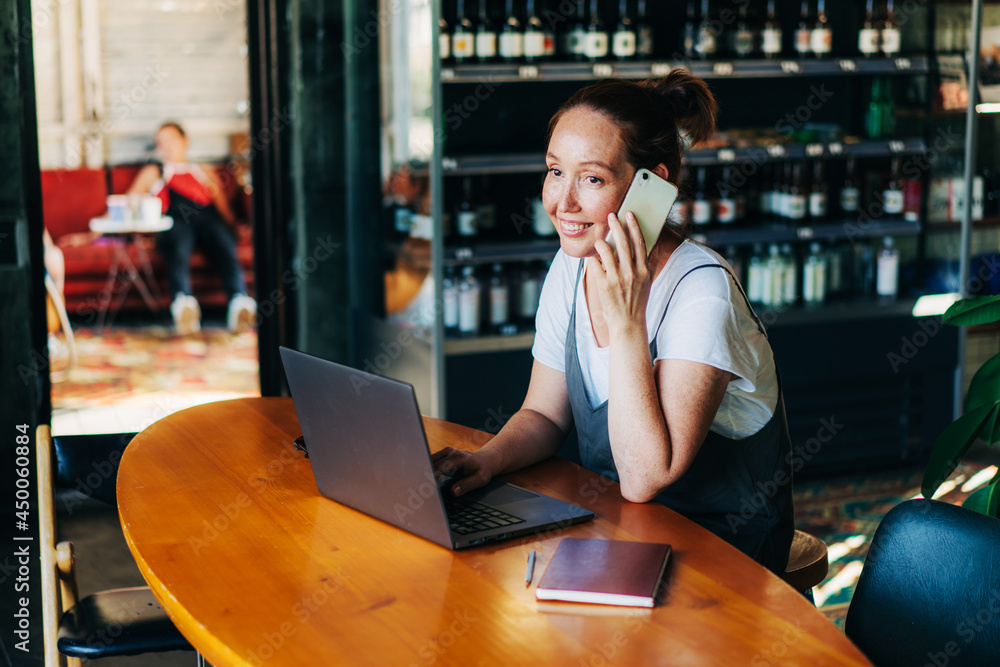 Woman manager talking on the phone while sitting in a cafe with a laptop, business negotiations. Woman manager talking on the phone while sitting in a cafe with a laptop, business negotiations.