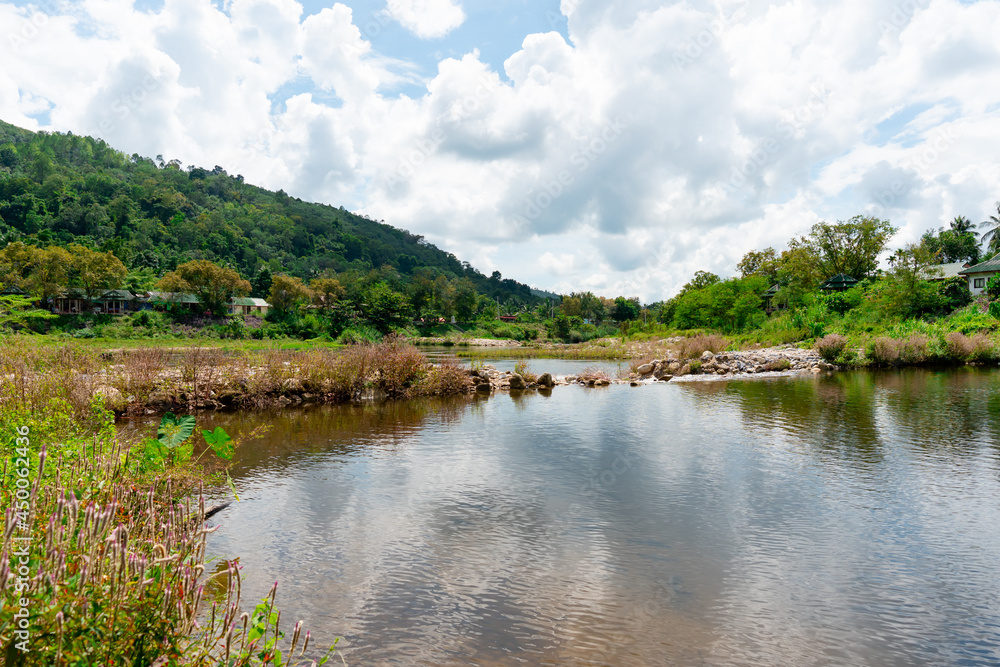 Obraz premium A view of a tourist attraction with a stream flowing behind a mountain sky with beautiful clouds.