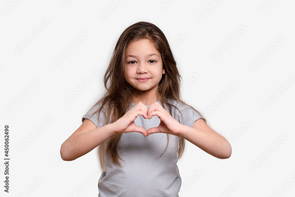 Friendship. Happy childhood concept, smiling. Little girl in white or grey blank t-shirts showing heart with hands. Hand love. Love symbol. Friendship. Happy childhood concept, smiling. Little girl in white or grey blank t-shirts showing heart with hands. Hand love. Love symbol.