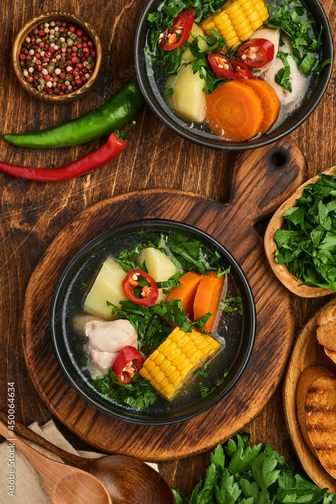 Chilean meat soup with pampkin, corn, fresh coriander and potatoes on old wooden table background. Cazuela. Latinamerican food. Chilean meat soup with pampkin, corn, fresh coriander and potatoes on old wooden table background. Cazuela. Latinamerican food.