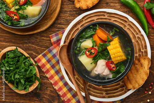 Chilean meat soup with pampkin, corn, fresh coriander and potatoes on old wooden table background. Cazuela. Latinamerican food.