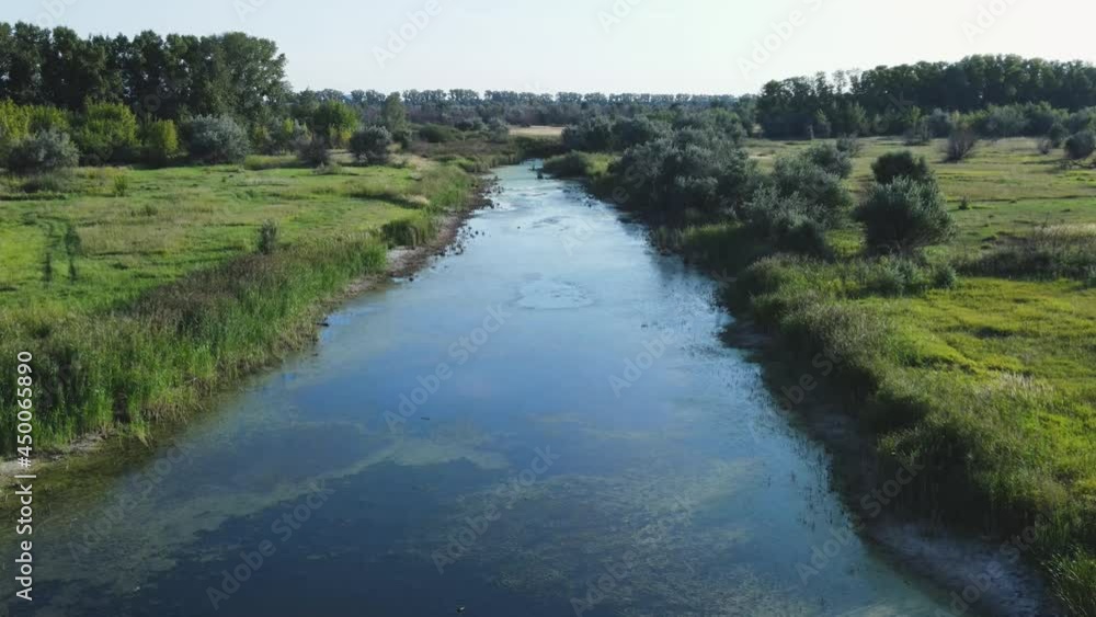 Aerial view of a beautiful rural landscape. The drone flies above a calm swampy lake surrounded by thickets of grass, trees and meadows. An atmosphere of tranquility alone with nature. Aerial view of a beautiful rural landscape. The drone flies above a calm swampy lake surrounded by thickets of grass, trees and meadows. An atmosphere of tranquility alone with nature.
