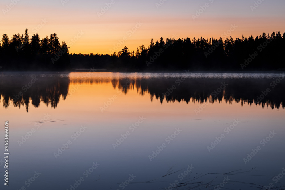 Colorful moody Sunset over lake with black silhouette of boreal forest  and beautiful reflection, Kitkajärvi, Posio, Finland