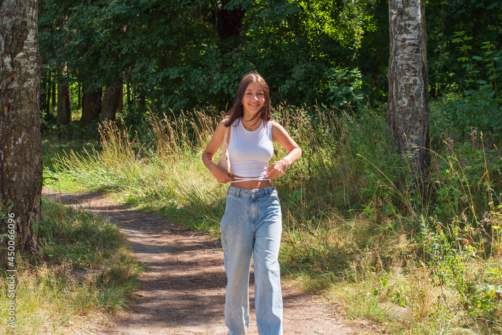 A teenage girl walks dreamily through a landscaped park on a beautiful sunny day. A teenage girl walks dreamily through a landscaped park on a beautiful sunny day.