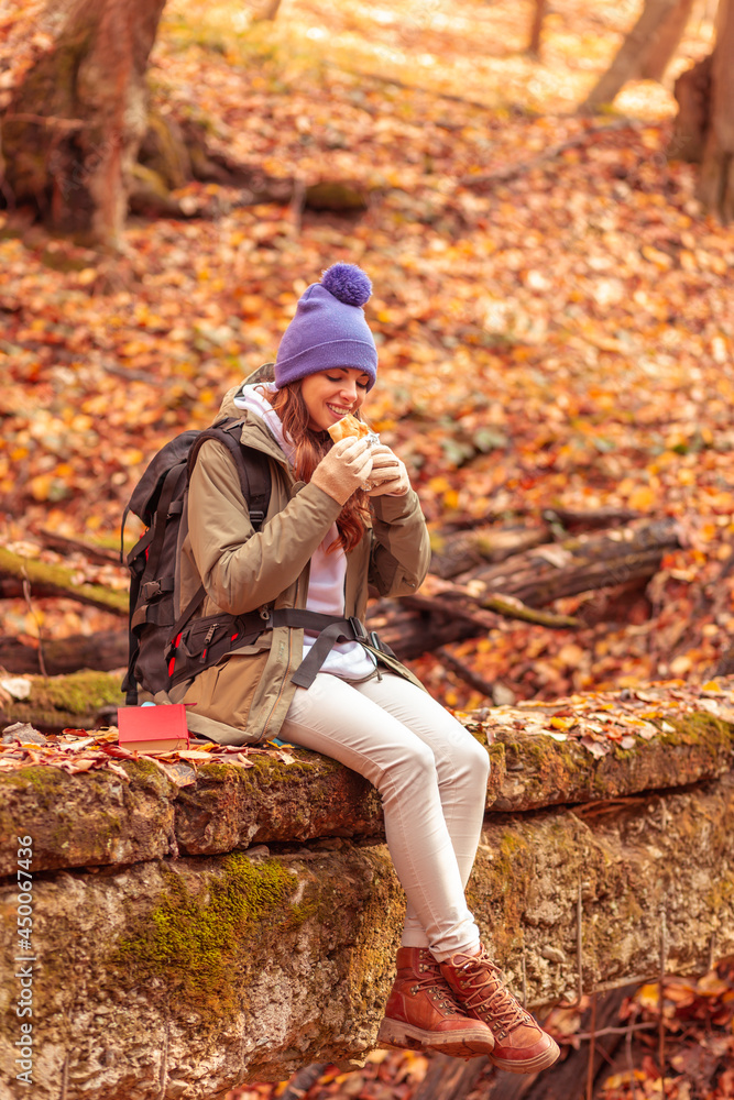 Woman eating a sandwich while taking a hiking break Woman eating a sandwich while taking a hiking break