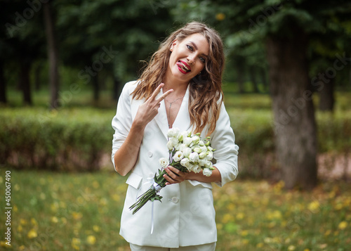 A girl in a white suit with a beautiful bouquet of flowers.