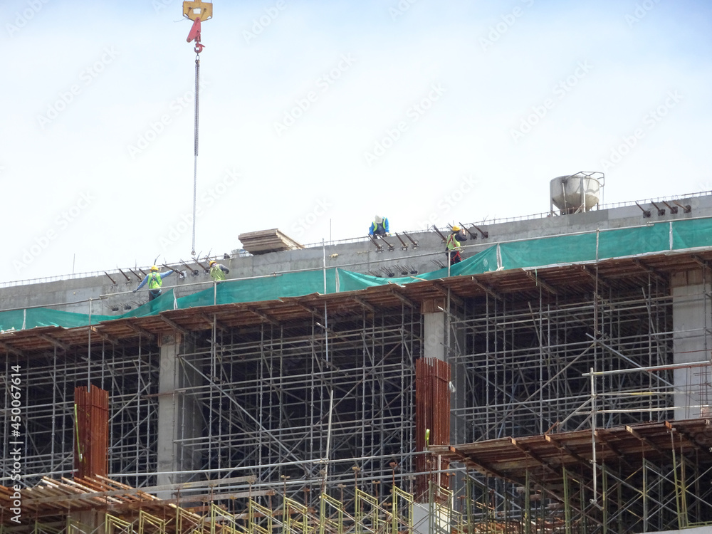 PENANG, MALAYSIA -JUNE 18, 2021: Structural works are underway at the construction site. Construction workers are installing formwork made of metal or timber. Safety features are paramount.
