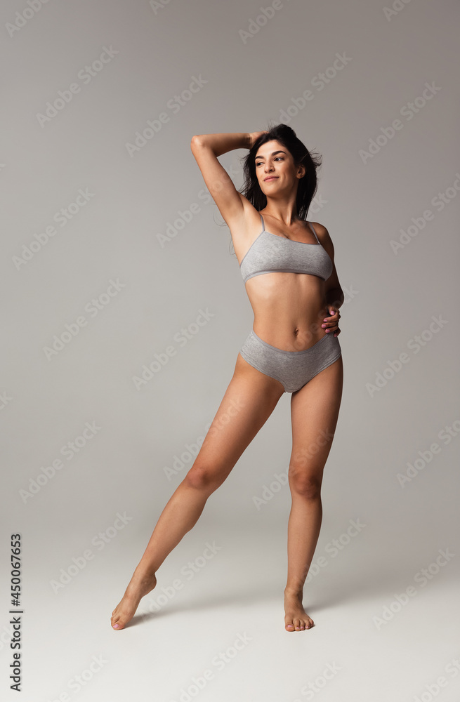 Portrait of young beautiful slim woman in lingerie posing isolated over gray studio background. Natural beauty concept. - obrazy, fototapety, plakaty 