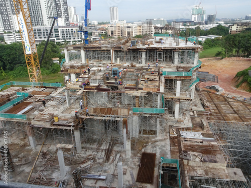 PENANG, MALAYSIA -JUNE 18, 2021: Structural works are underway at the construction site. Construction workers are installing formwork made of metal or timber. Safety features are paramount.  © Aisyaqilumar