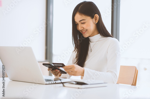 Woman holding smart phone and credit card for shopping online.Blank screen monitor for graphic display montage.Pay for goods by credit card through a smartphone . © David