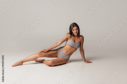 Young adorable woman in lingerie isolated over gray studio background. Natural beauty concept.