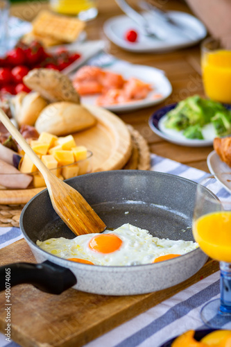 Fried eggs in a skillet on a large table filled with food.Fried eggs in a skillet for breakfast for a large family.Lots of eggs in a skillet for a large family.Breakfast table.Summer breakfast.Dinner 
