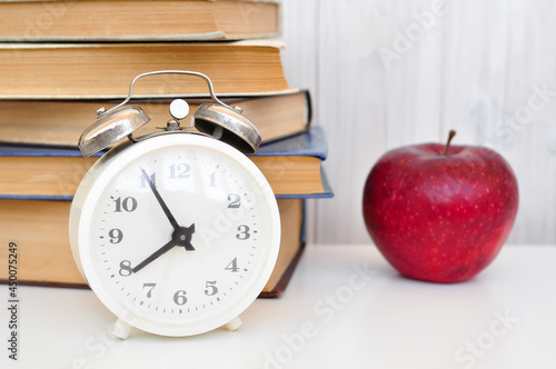 alarm clock, red apple and books work and study morning concept