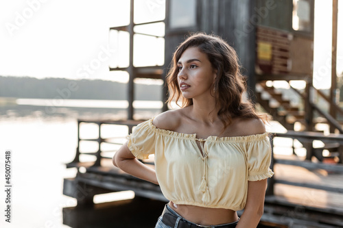 Summer portrait of a beautiful young curly woman in a yellow top blouse walking on the beach © alones