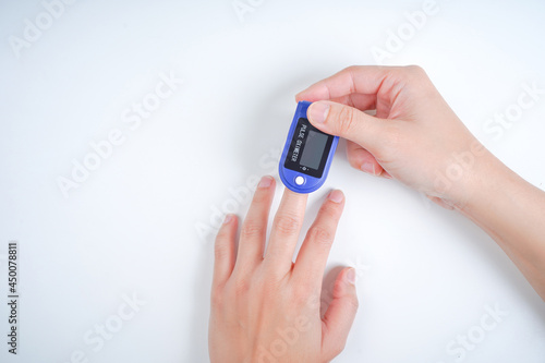 Woman using fingertip pulse oximeter, closeup.
