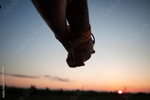 Romantic couple holding hands in summer field at sunset