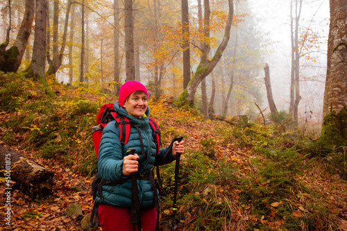 Happy woman hiker is walking in the beautiful autumn forest