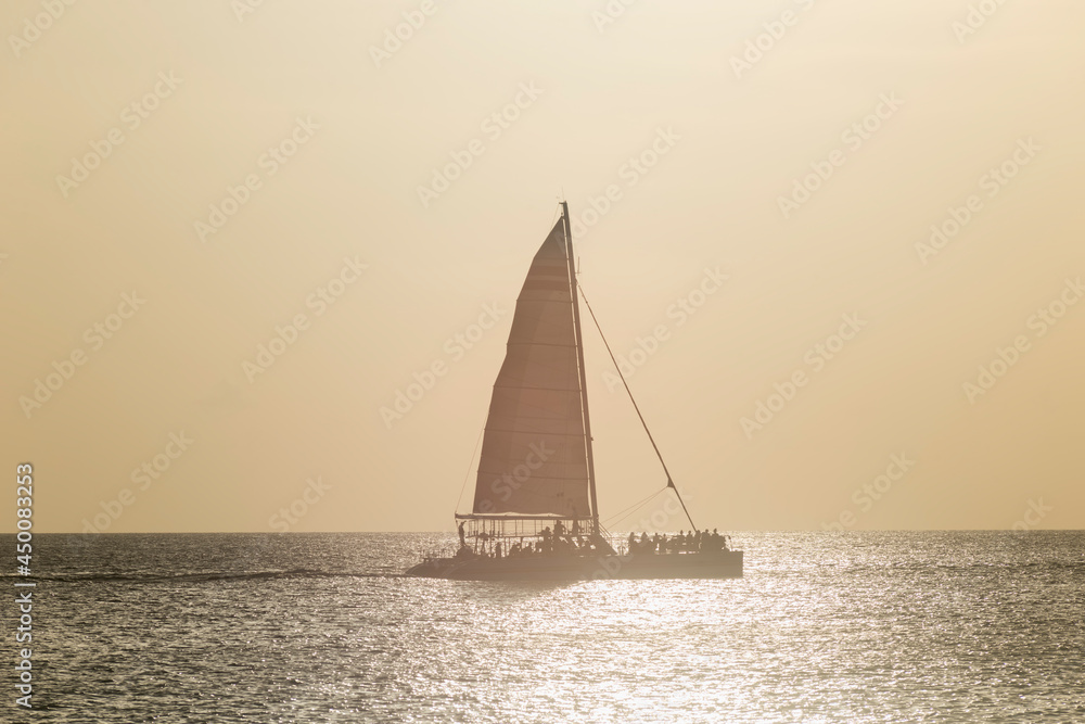 A catamaran sails at sunset in the Caribbean Sea near the tropical island of Cozumel in Mexico