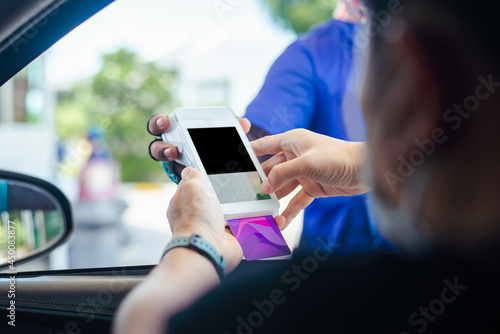 Gas station worker swipe mockup credit card via payment terminal after giving a price quote to the customer sitting in the car. photo