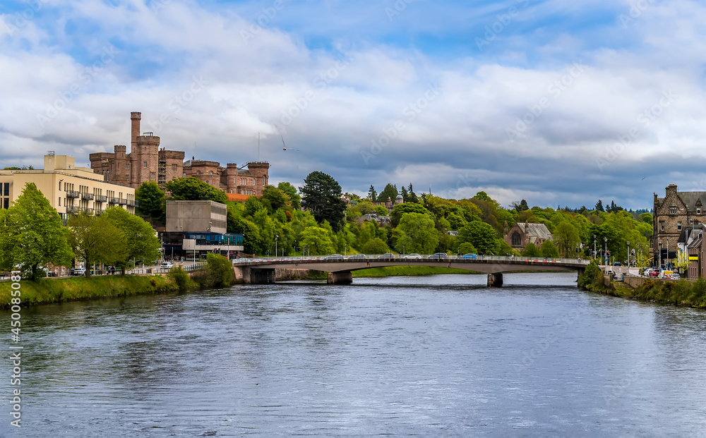 Fototapeta premium A view down the River Ness towards castle and the Ness Bridge in Inverness, Scotland on a summers day