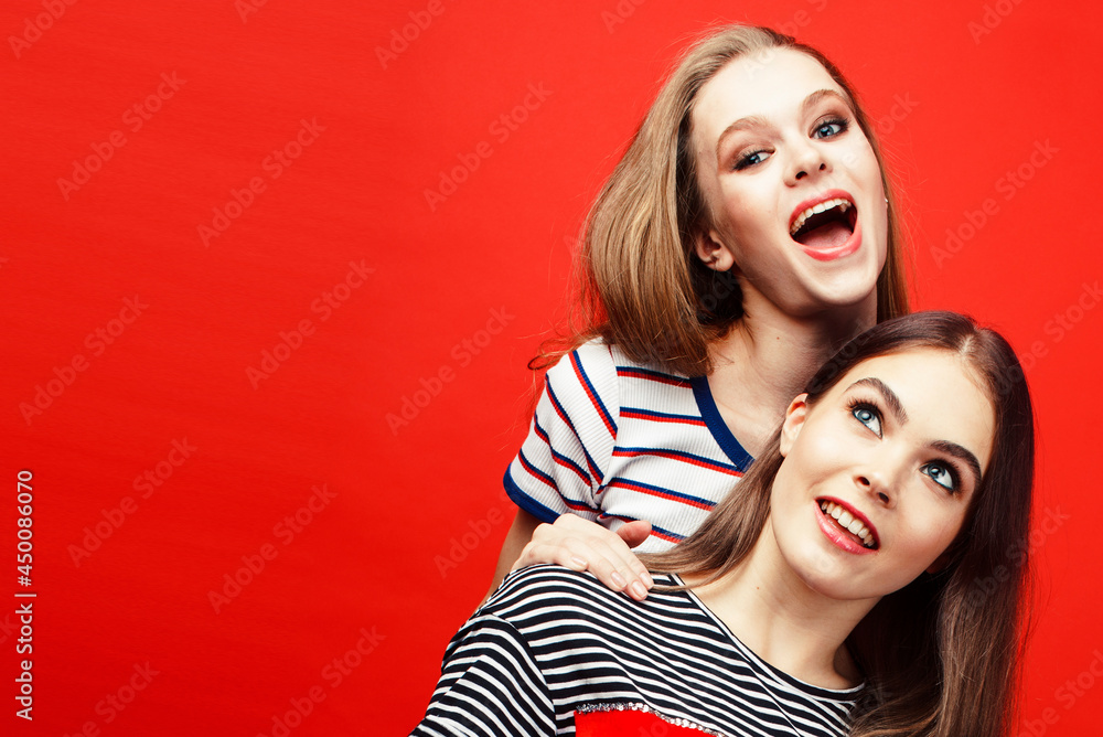 two best friends teenage girls together having fun, posing emotional on red background, lifestyle people concept two best friends teenage girls together having fun, posing emotional on red background, lifestyle people concept