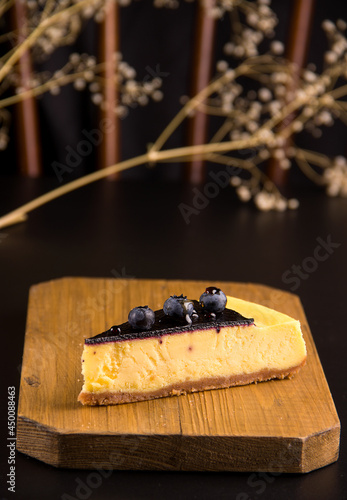 The concept of cakes. Cheesecake with blueberries and caramel on a black background
