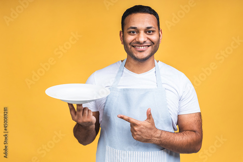 Obraz na plátně Indian african american chef cook or baker man in striped apron isolated over yellow background