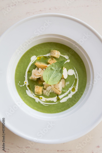 Green vegetarian cream soup served in white plate