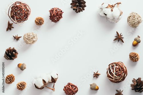 Autumn composition. Frame made of cotton, pine cones, anise, ball decorations on white background. Flat lay, top view, copy space.