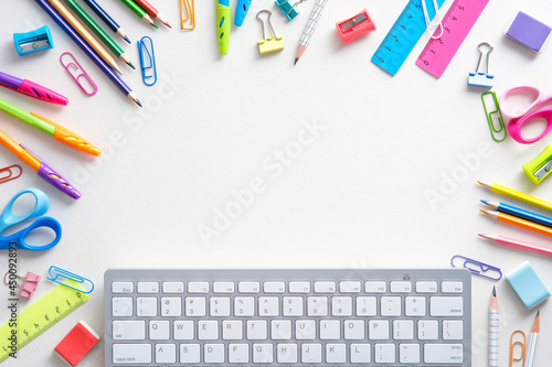 School supples and keyboard on white background. Flat lay, top view colorful stationery. E-learning, online school concept. photo
